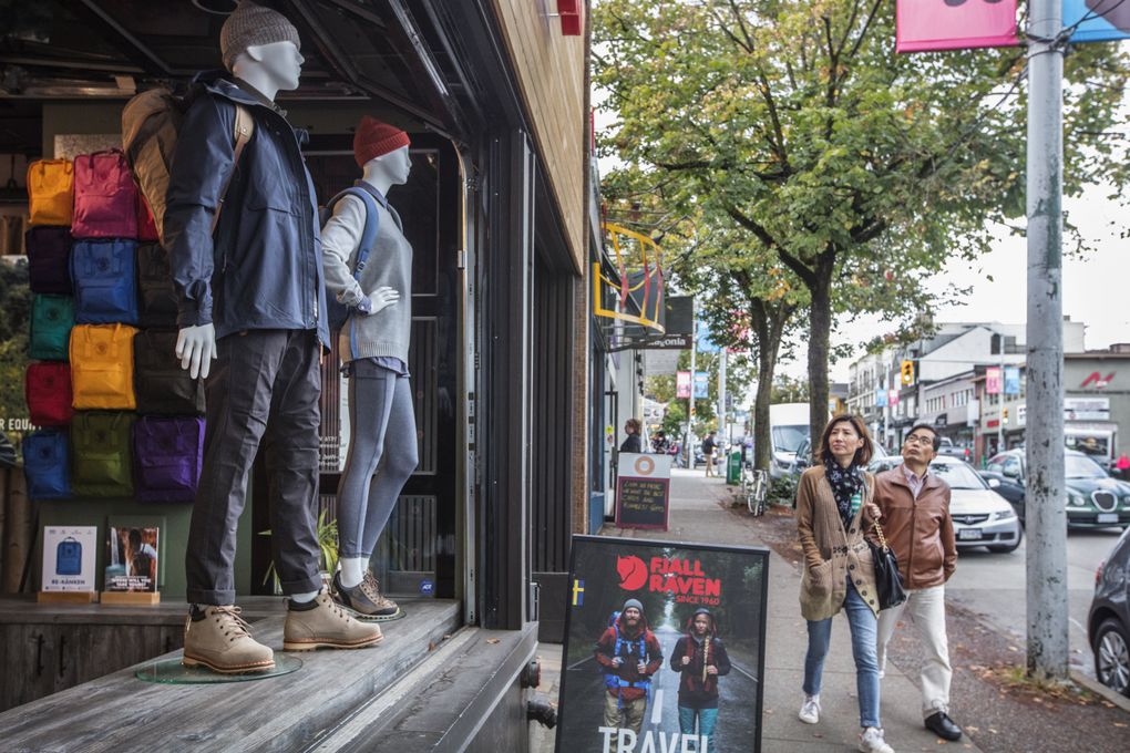Shoppers walk along West Fourth Avenue looking up at the Fjall Raven store in the Kitsilano District. (Steve Ringman/The Seattle Times)