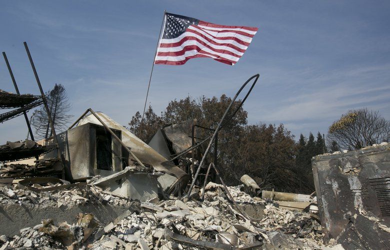 A United States flag flies over the charred remains of a house in the Coffey Park area of Santa Rosa, Calif., Monday, Oct. 16, 2017. (AP Photo/Rich Pedroncelli) CARP101 CARP101