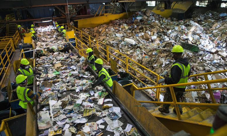 Quality-control employees sort through recyclable items at Republic Services’ vast Seattle recycling center recently.  (Ellen M. Banner/The Seattle Times)