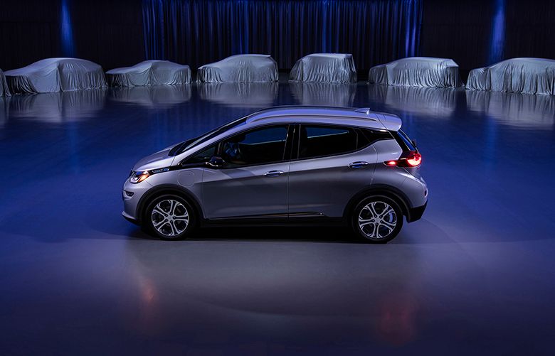 This photo provided by General Motors Co. shows a Chevrolet Bolt, surrounded by nine electric and fuel cell vehicles covered by tarps. On Monday, Oct. 2, 2017, GM announced the company will produce two new electric vehicles on the Bolt underpinnings in the next 18 months and 20 electric and hydrogen fuel cell vehicles by 2023. (Courtesy of General Motors Co. via AP)