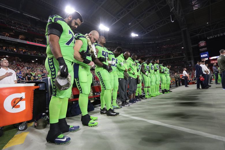 Michael Bennett, all Seahawks, stand for the national anthem on