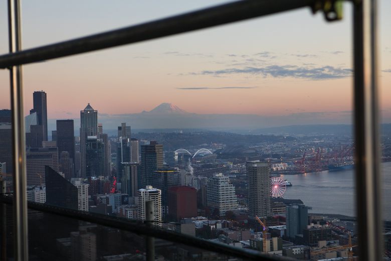 A picture-perfect view of Seattle’s skyline and Mount Rainier is visible through the scaffolding hanging below the restaurant on the Space Needle. (Ellen M. Banner/The Seattle Times)