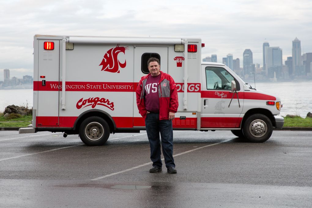 Paul Twibell stands with his WSU fan vehicle, the Cougulance, on Alki Beach in Seattle. Everybody asks what that clear liquid is, he says, in the IV drips that still hang inside. (Ramon Dompor / The Seattle Times)