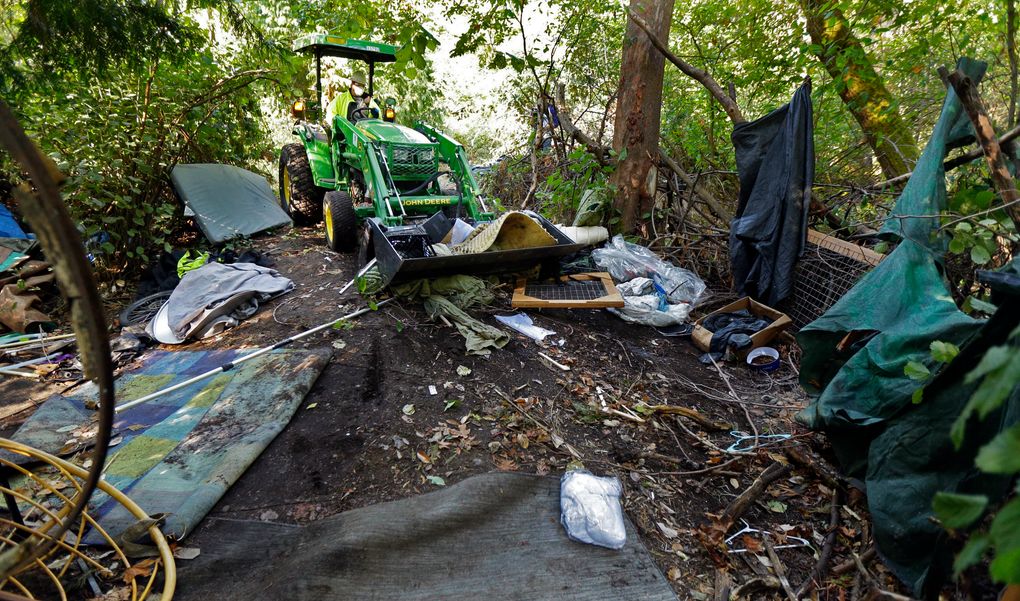 A worker uses a tractor to clear a large homeless encampment in the woods near Seattle’s Ravenna Park neighborhood. Residents were given notice and offered shelter beds and other services, but some people in the encampment did not remove their belongings before the cleanup began. (AP Photo/Ted S. Warren)