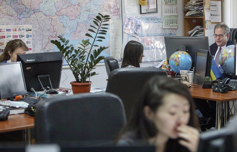 Kyiv Post chief editor Brian Bonner, right, and other journalists work at their desks in Kiev, Ukraine, on Friday, Dec. 8, 2017. Bonner and several other members of his newsroom staff were targeted by the group widely known as Fancy Bear, an Associated Press investigation has found. (AP Photo/Volodymyr Petrov) NY583 NY583