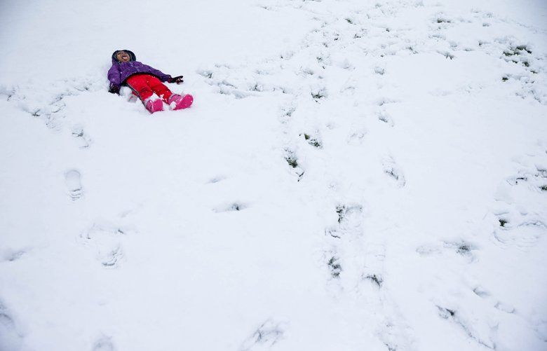 Soliyana Miheretu (4) makes a snow angel and sticks out her tongue to catch snowflakes which she says taste yummy like chocolate milk at Roxhill Park, in Seattle, on Christmas morning, Dec. 25, 2017. The last time there was measurable snow on Christmas was in 2008 after a storm left 4 inches. 
 204663