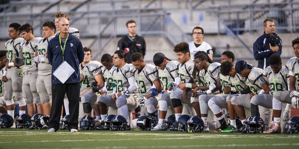 Todd Beamer coach Darren McKay stands beside a portion of his team that chose to kneel during the national anthem Friday, September 29, 2017 at Auburn Memorial Stadium. (Dean Rutz / The Seattle Times)