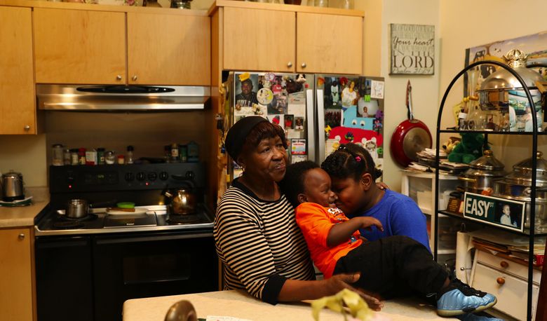 Dixie Mitchell sits with two of her great-grandchildren, Zion Russell, 8, right, and Zaydhen Butler, 2, in the kitchen of the house she fought to save from debtors during the economic downturn. “They came and tried to snatch my house out from under me,” she says. (Ken Lambert/The Seattle Times)