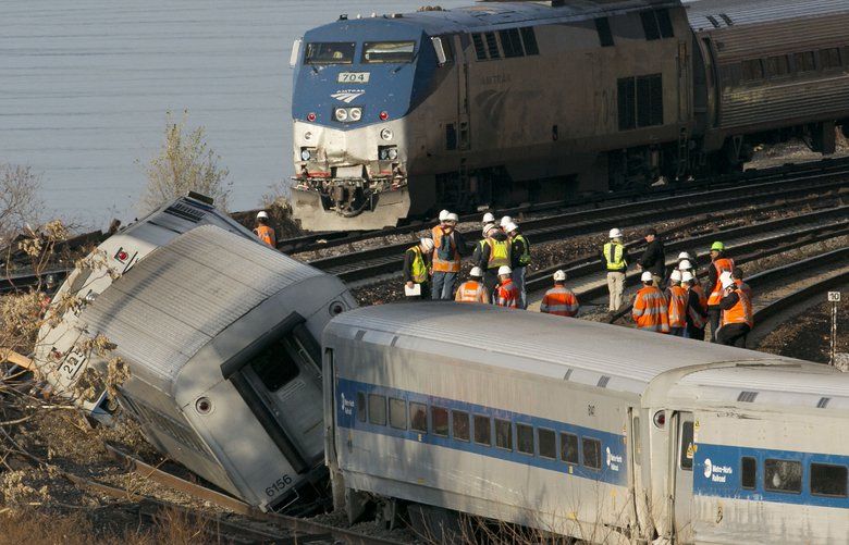FILE – In a Dec. 1, 2013, file photo, an Amtrak train, top, traveling on an unaffected track, passes a derailed Metro North commuter train, in the Bronx borough of New York. President Donald Trump is putting the brakes on attempts to address dangerous transportation safety problems from speeding tractor-trailers to sleepy railroad engineers as part of his quest to roll back regulations across the government. (AP Photo/Mark Lennihan, File) WX202 WX202