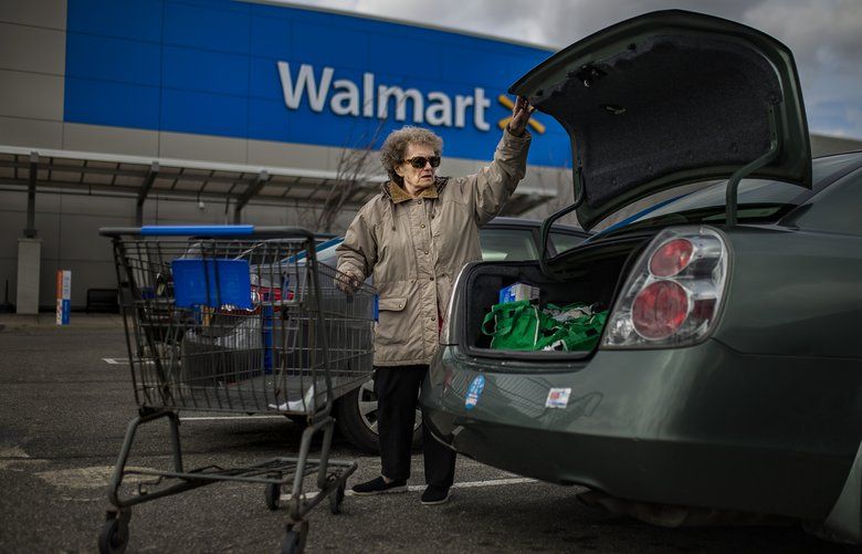 A woman loads her car after shopping at a  Walmart store.