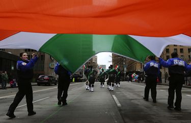 In gusting winds, the Seattle Police Explorers hang onto a giant flag of Ireland as they head north on Fourth Avenue in the 2015 St. Patrick’s Day Parade. This year’s march starts at 12:30 p.m. Saturday, March 17.  (Alan Berner/The Seattle Times)