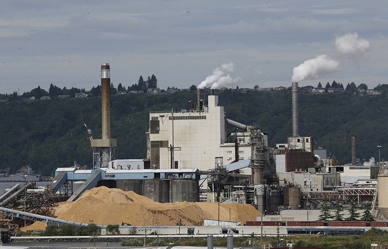 Piles of wood chips sit near the RockTenn paper mill, Wednesday, June 1, 2016, in Tacoma, Wash. Washington state regulators released an updated plan Wednesday to limit greenhouse gas emissions from large polluters, including the mill, as the latest attempt by Gov. Jay Inslee to push ahead with a binding cap on carbon emissions after struggling to win approval from legislators. (AP Photo/Ted S. Warren)