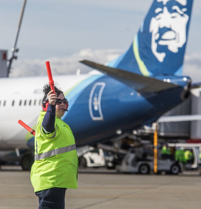 McGee Air Services employee Jennifer Brown assists an Alaska Airlines plane headed out to San Francisco. (Steve Ringman/The Seattle Times)