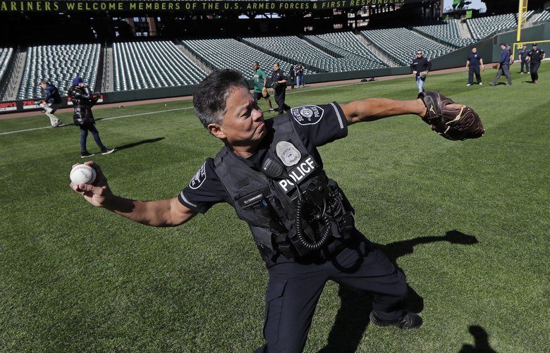 Seattle Police officer Jojo Cambronero plays catch on the new grass at Safeco Field in Seattle, Tuesday, March 20, 2018. The home stadium of the Seattle Mariners baseball team invited a group of police and fire first responders and members of the military to be the first people to play catch on the new grass, which was replaced last fall for the first time since the ballpark opened in 1999. (AP Photo/Ted S. Warren) WATW105 WATW105