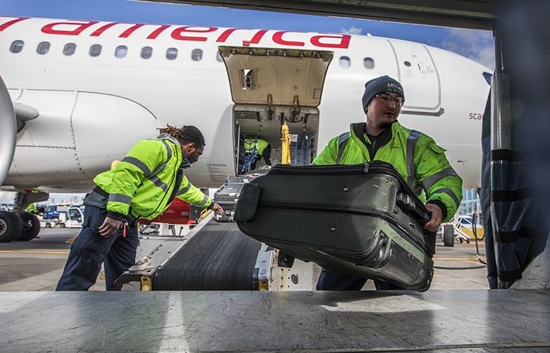 Friday, March 9, 2018.   McGee Air Services employees toss bags into a cart from a Virgin America plane that has just landed at SeaTac Airport.