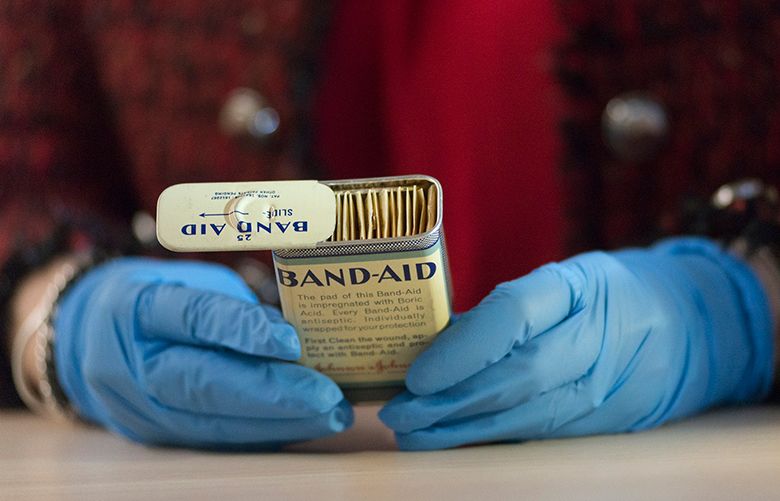 Margaret Gurowitz, the chief historian for Johnson & Johnson, handles a vintage box of Band-Aids with rubber gloves in the company’s museum in New Brunswick, New Jersey. (Christopher Occhicone / The New York Times)