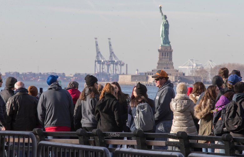FILE – In this Jan. 20, 2018, file photo, visitors to the Statue of Liberty stand in line to board a ferry that will cruise the bay around the statue and Ellis Island in New York. The U.S. Department of Commerce says government statistics showing a decrease in international arrivals may be wrong. The department is suspending publication of the data until it can be revised. Critics have been complaining of a “Trump slump” in international tourism, and arrivals data compiled by the government had validated those concerns until now. The Commerce Department says some international arrivals may have been miscategorized as U.S. residents, leading to an undercount. (AP Photo/Mary Altaffer, File) NYLS202 NYLS202