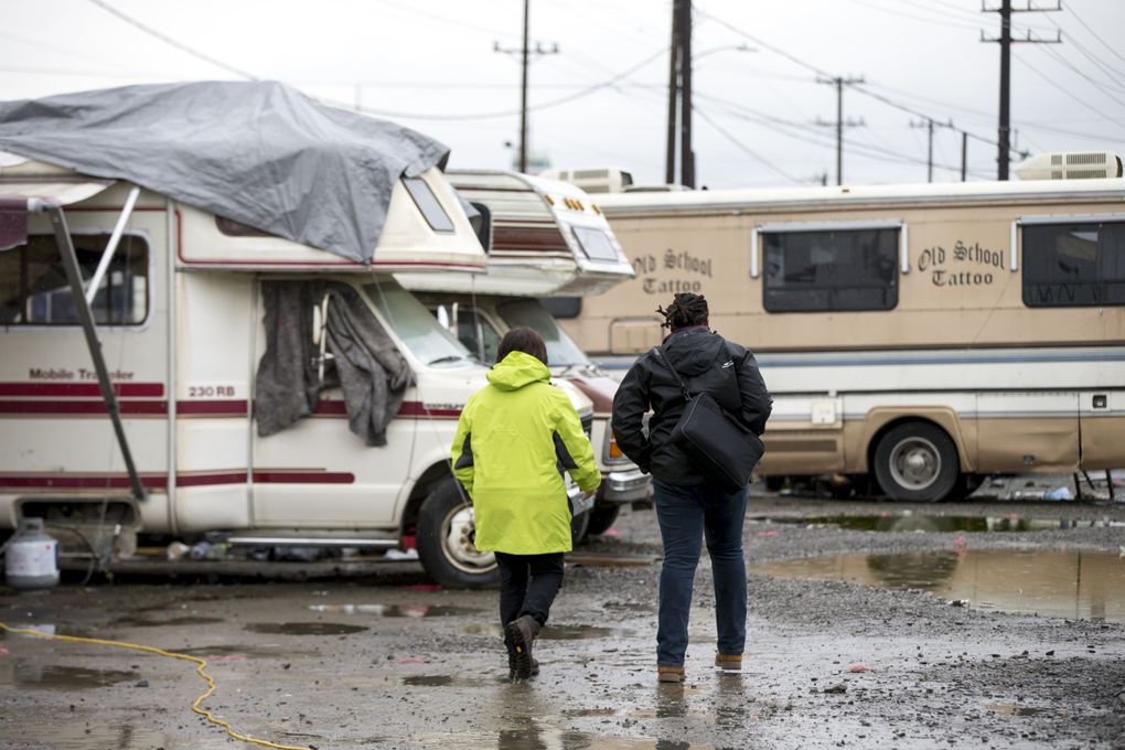 Jackie St. Louis, right, walks with a fellow city employee to check on residents in the city of Seattle’s last safe parking zone, at Second Avenue South and South Spokane Street in Sodo. St. Louis leads the city’s Navigation Team, doing outreach with people living in homeless encampments. In January, he was tapped to also help residents of the vehicle safe zone connect to services and, hopefully, housing. (Bettina Hansen/The Seattle Times)