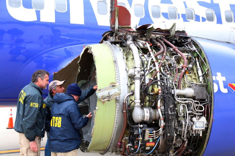 National Transportation Safety Board investigators examine damage to the engine of the Southwest Airlines plane that made an emergency landing at Philadelphia International Airport in Philadelphia on Tuesday, April 17, 2018. The Southwest Airlines jet blew the engine at 32,000 feet and got hit by shrapnel that smashed a window, setting off a desperate scramble by passengers to save a woman from getting sucked out. She later died, and seven others were injured. (NTSB via AP)