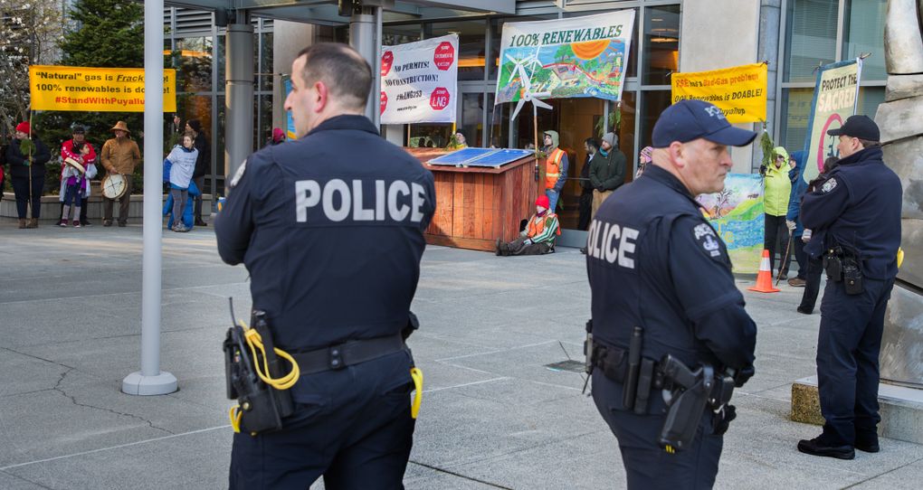Bellevue police stand by as demonstrators chain themselves to a structure blocking the front door of Puget Sound Energy’s headquarters to protest that PSE is building a liquefied natural gas (LNG) facility at the Port of Tacoma. (Mike Siegel/The Seattle Times)