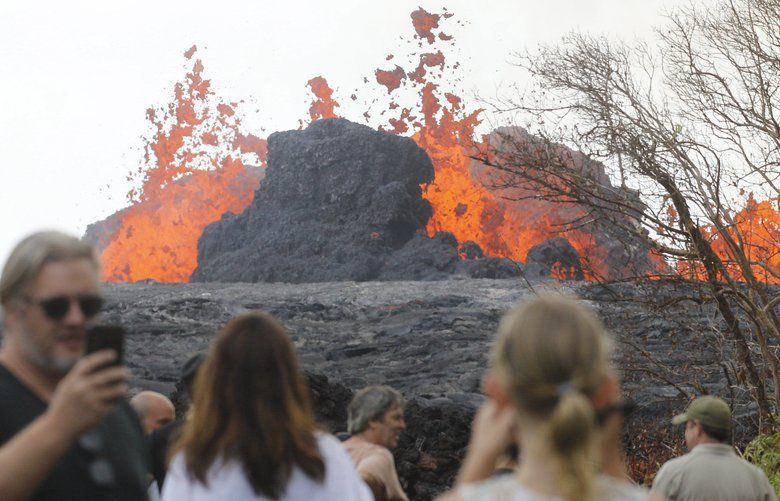 In a Saturday, May 26, 2018 photo, area residents, the media and national guard flock to what is now the end of Leilani Avenue to take in the fiery show at fissures 2, 7 and 8 of the Kilauea volcano near Pahoa.  (George F. Lee/The Honolulu Advertiser via AP) HIHAD101 HIHAD101
