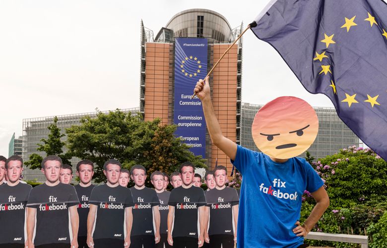 An Avaaz demonstrator waves the European flag as he stands next to life-sized Zuckerberg cutouts to protest against fake Facebook accounts spreading disinformation on the platform, near the EU Commission in Brussels, Tuesday, May 22, 2018. European Union lawmakers plan to press Facebook CEO Mark Zuckerberg on Tuesday about data protection standards at the internet giant at a hearing focused on a scandal over the alleged misuse of the personal information of millions of people. (AP Photo/Geert Vanden Wijngaert)