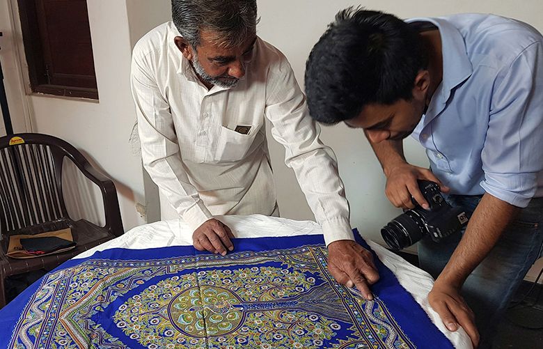Abdul Gafur Khatri, left, displays his Rogan art piece “Tree of Life” for a photograph at the Amazon.com Inc. seller workshop in Bhuj, India, on Saturday, April 28, 2018. In the town of Bhuj, tucked into a remote region that abounds with handmade crafts, Amazon.com Inc. is venturing here. Amazon is offering workshops to initiate some of the most talented – and least tech savvy – artisans in the mysteries of online selling. Photographer: Saritha Rai/Bloomberg