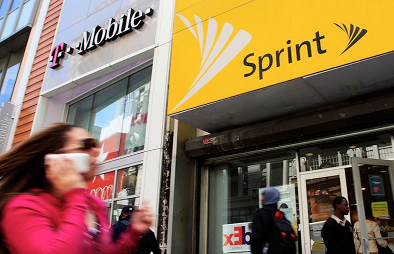 A woman using a cell phone walks past T-Mobile and Sprint stores, Tuesday, April 27, 2010, in New York.