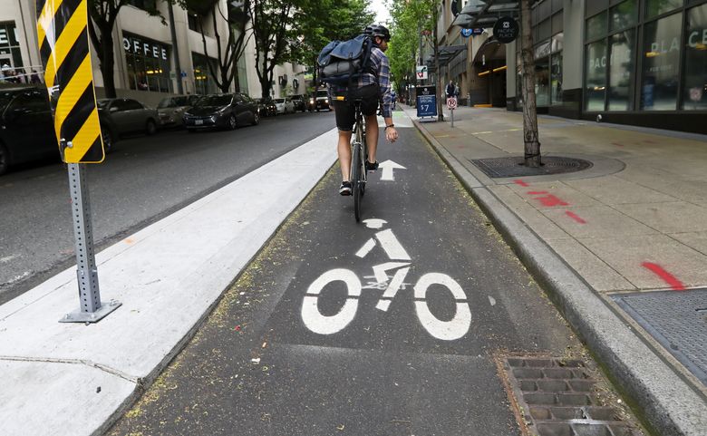 It’s not just the bike lane itself that costs money; signage, islands, drainage and more add up. A cyclist pedals between a storm drain and an island along the new Seventh Avenue bike lane on Thursday. The total came to $3.8 million for one-third of a mile there. (Ken Lambert / The Seattle Times)
