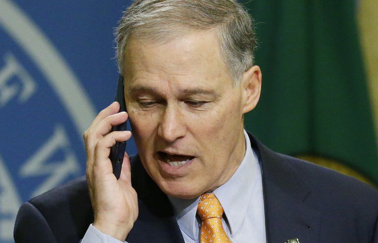 Washington Gov. Jay Inslee, left, briefly speaks into his phone after it rang during a news conference, Thursday, Feb. 23, 2017, at the Capitol in Olympia, Wash., as general counsel Nick Brown looks on at right. Inslee signed an executive order Thursday to ensure that state workers don’t help carry out President Donald Trump’s immigration policies. (AP Photo/Ted S. Warren) WATW108 WATW108