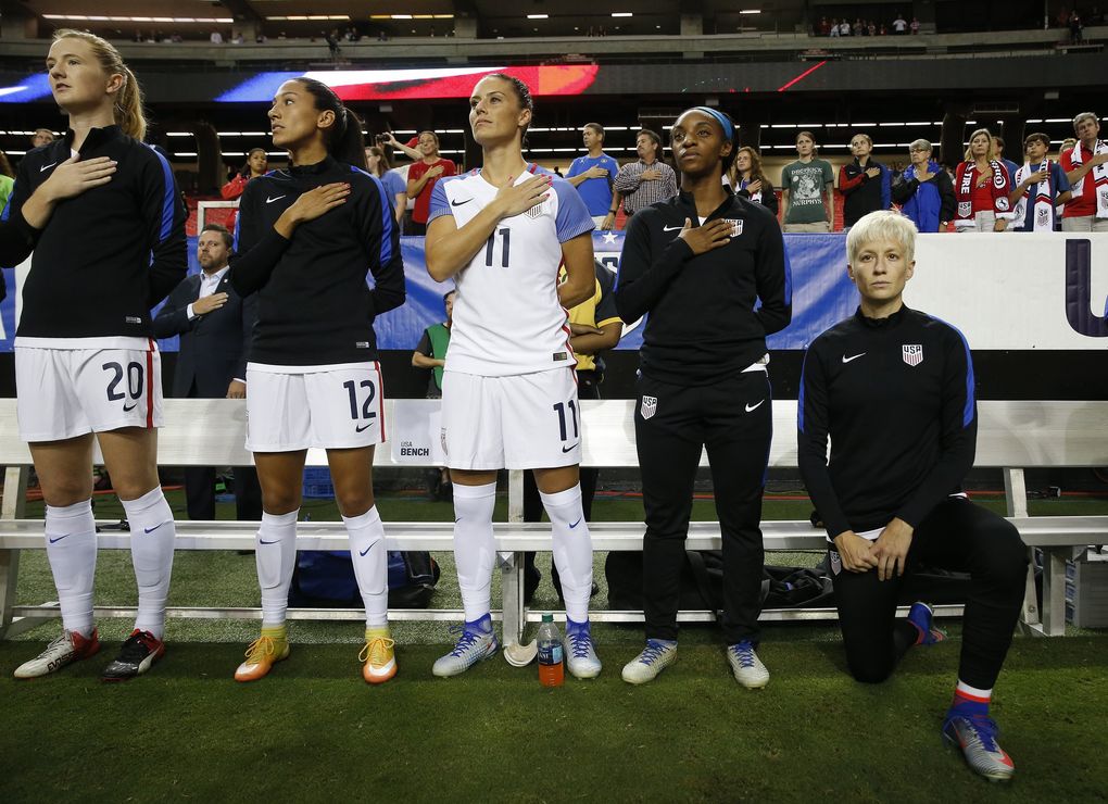 USA’s Megan Rapinoe, right, kneels next to teammates as the national anthem is played before a soccer match in September 2016. (AP Photo/John Bazemore, file)