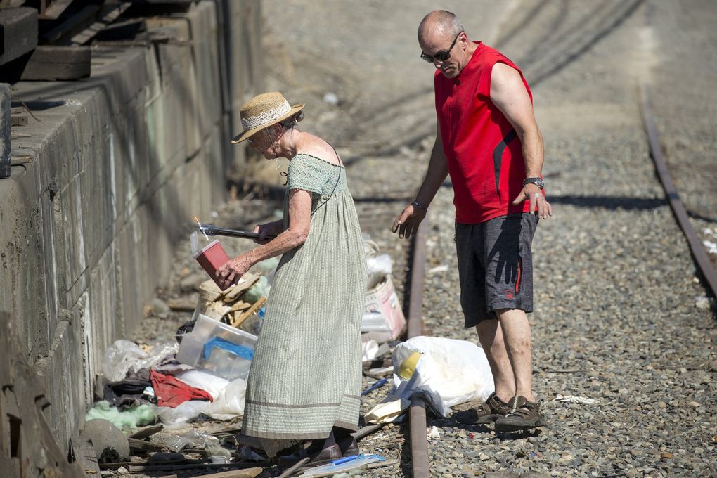 Jody Grage uses kitchen tongs to pick up needles Monday while Brad Wright picks up trash off Shilshole Avenue in Ballard. Wright used to be homeless until Grage put him up in her trailer in Ballard. Wright started picking up trash when he was homeless, to engender goodwill from the community. (Bettina Hansen / The Seattle Times)