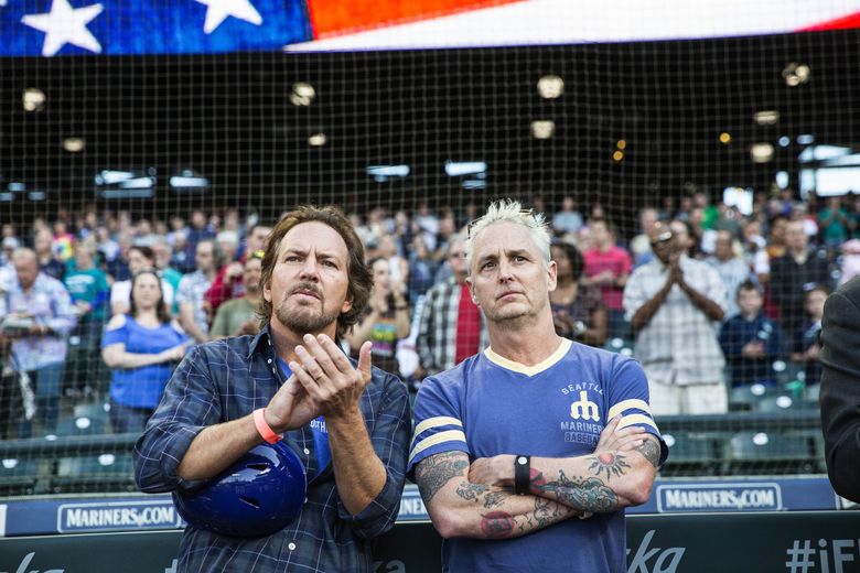 Pearl Jam’s Eddie Vedder, left, and Mike McCready listen to performers from Path with Art perform the National Anthem Friday at Safeco Field. (Dean Rutz / The Seattle Times)