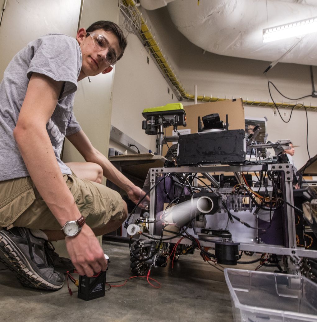 A white streak appears from the barrel of the “hero” robot as it fires golf balls while overseen by Sig Johnson. (Steve Ringman/The Seattle Times)