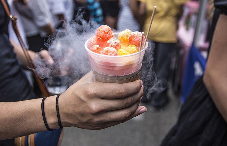 A customer holds a dessert fresh from food stand 320 below, which freezes its dishes in liquid nitrogen, before giving it a try during Seattleâ€™s largest food truck festival in South Lake Union, on July 7, 2018.