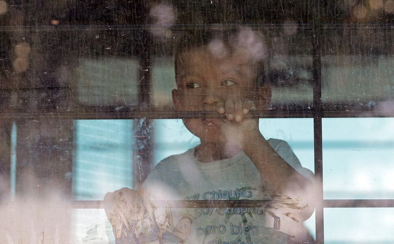 File – In this June 23, 2018, file photo, an immigrant child looks out from a U.S. Border Patrol bus leaving as protesters block the street outside the U.S. Border Patrol Central Processing Center in McAllen, Texas. Immigrant children described hunger, cold and fear in a voluminous court filing about the facilities where they were held in the days after crossing the border. Advocates fanned out across the southwest to interview more than 200 immigrant parents and children about conditions in U.S. holding facilities, detention centers and a youth shelter. The accounts form part of a case over whether the government is complying with a longstanding settlement over the treatment of immigrant youth in custody. (AP Photo/David J. Phillip, File)