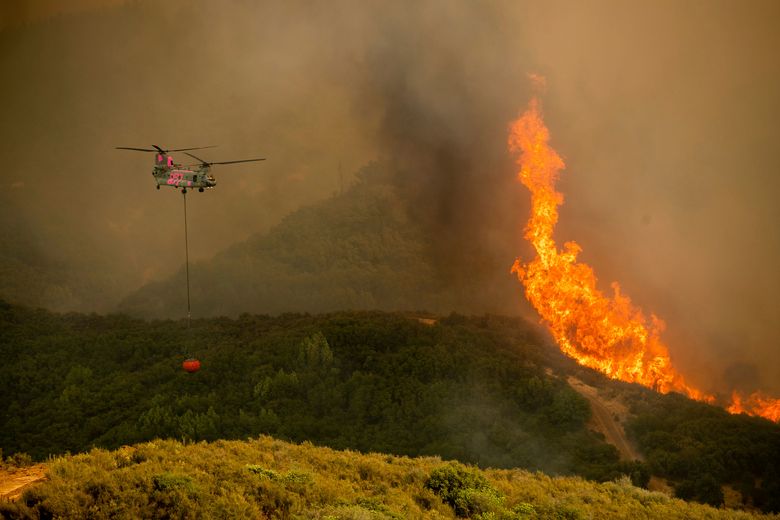 A helicopter carries water while battling the River Fire burning in Lakeport, Calif., Tuesday, July 31, 2018. Firefighters pressed their battle against a pair of fires across Mendocino and Lake counties. In all, roughly 19,000 people have been warned to flee and 10,000 homes remain under threat. (AP Photo/Noah Berger)