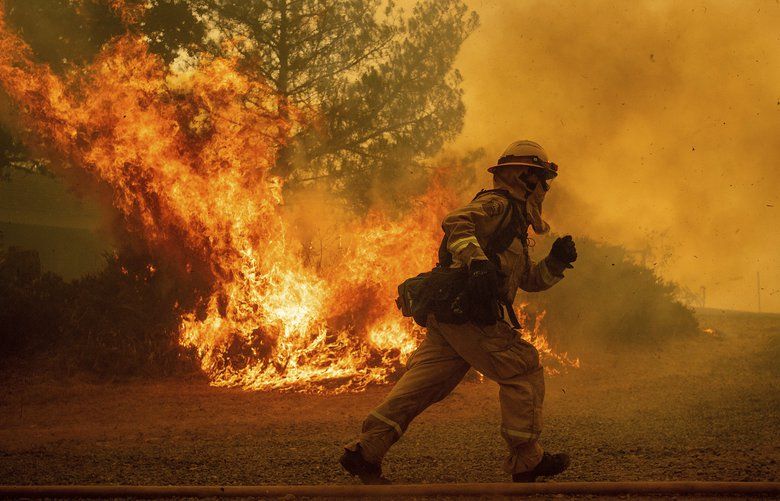 REMOVES NAME OF STREET AS STREET NAME IS UNKNOWN – A firefighter runs while trying to save a home as a wildfire tears through Lakeport, Calif., Tuesday, July 31, 2018. The residence eventually burned. Firefighters pressed their battle against a pair of fires across Mendocino and Lake counties. In all, roughly 19,000 people have been warned to flee and 10,000 homes remain under threat. (AP Photo/Noah Berger) CANB107 CANB107