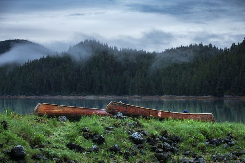 Every day of the 2017 Inside Passage journey, the four men pulled their canoes onto shore above the high-tide line. Here they sit on a grassy bank in the Santa Ana Inlet in Alaska while mist dances over the hillside on the opposite bank. (Nate Dappen)