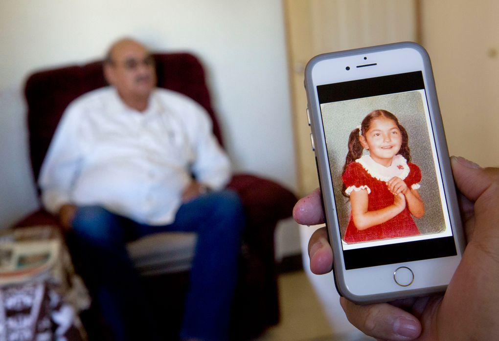A photo of Monica Still Smoking is shown on a cellphone as her father, Kenny Still Smoking, sits in the background at his home on the Blackfeet Indian Reservation in Browning, Mont. Monica disappeared in 1979 from her school at the age of seven. She was later found frozen to the mountain 20 miles away. No one has ever been arrested. (David Goldman/AP)
