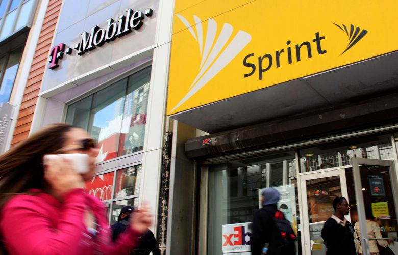 A woman using a cell phone walks past T-Mobile and Sprint stores, Tuesday, April 27, 2010, in New York. Sprint Nextel Corp. on Wednesday, April 28, said it lost a net 75,000 subscribers in the first three months of 2010, compared to a loss of 182,000 in the same quarter last year.(AP Photo/Mark Lennihan) 