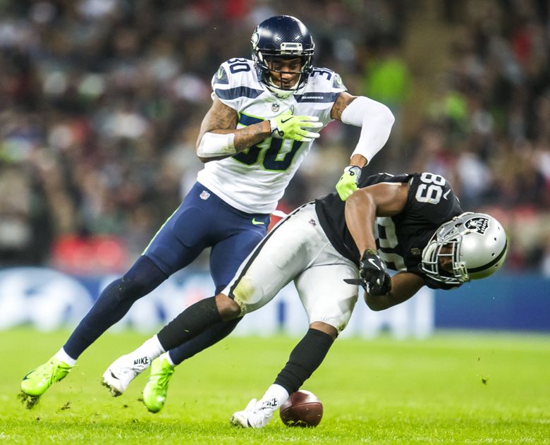 An Oakland Raiders player holds up a helmet at the start of a NFL preseason  football game again …