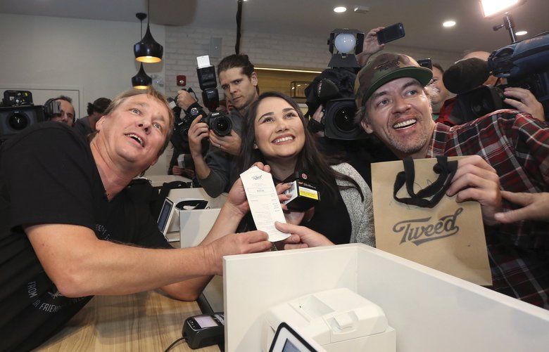 Canopy Growth CEO Bruce Linton, left to right, poses with the receipt for the first legal cannabis for recreation use sold in Canada to Nikki Rose and Ian Power at the Tweed shop on Water Street in St. John’s N.L. at 12:01 am NDT on Wednesday Oct. 17, 2018. (Paul Daly/The Canadian Press via AP) PD663 PD663