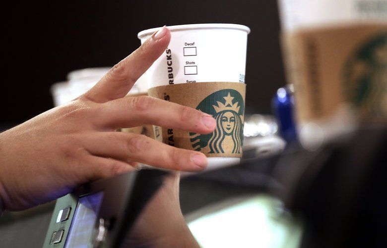 FILE – In this May 29, 2018, file photo, a barista reaches for an empty cup at a Starbucks in the Pike Place Market in Seattle. Starbucks has opened its first U.S. “signing store” to better serve hard of hearing customers. The store in Washington, D.C. is just blocks from Galludet Univerisity, one of the nation’s oldest universities serving deaf and hard of hearing students. (AP Photo/Elaine Thompson, File) NYBZ231 NYBZ231