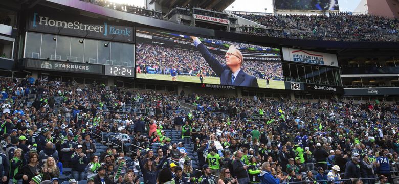 Seattle Seahawks owner Paul Allen, left, shakes hands with former Seahawks  tackle Walter Jones next to Jones' #71 jersey during a halftime ceremony to  induct Jones into the Seahawks Ring of Honor