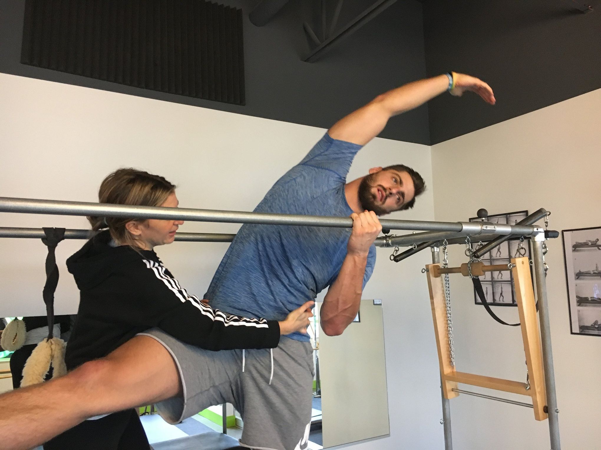 Male athlete with hands behind head practicing pilates on cadillac