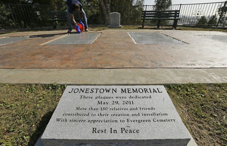 In this Thursday, Oct. 25, 2018, photo, former Peoples Temple member Jim Jones Jr. places bleached rocks around the edges of the Jonestown victim memorial in the Evergreen Cemetery in Oakland, Calif. Ceremonies were held at the cemetery to mark the mass murders and suicides 40 years earlier of more than 900 Americans orchestrated by the Rev. Jim Jones at a jungle settlement in Guyana, South America. The unclaimed or unidentified remains of more than 400 victims of the Jonestown tragedy on Nov. 18, 1978, are buried at the cemetery. (AP Photo/Eric Risberg) FX802 FX802