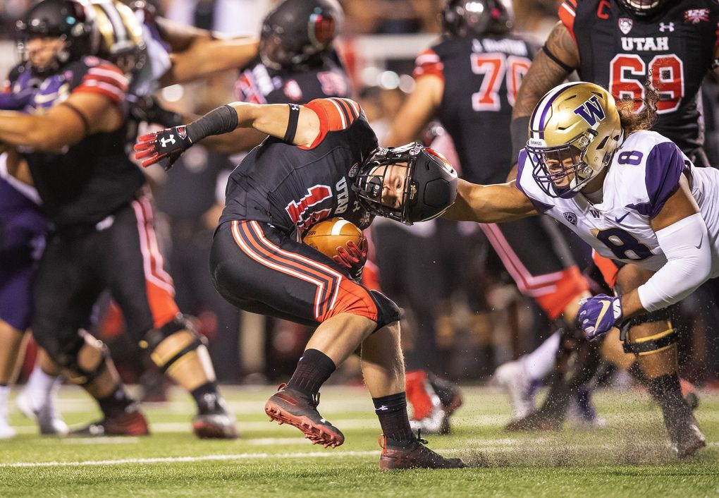 Washington’s Benning Potoa’e tackles Utah’s Britain Covey by the back of the neck in September. (Dean Rutz / The Seattle Times)
