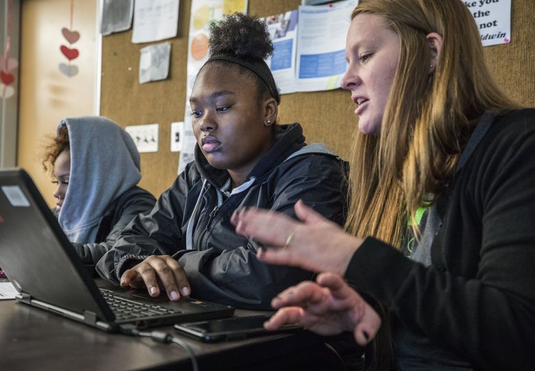 Cleveland High School head counselor Avery Kamau, right, helps seniors Jaida Jahmid, left, and Breona Devers, both 17, apply for financial aid to attend college. (Steve Ringman / The Seattle Times)