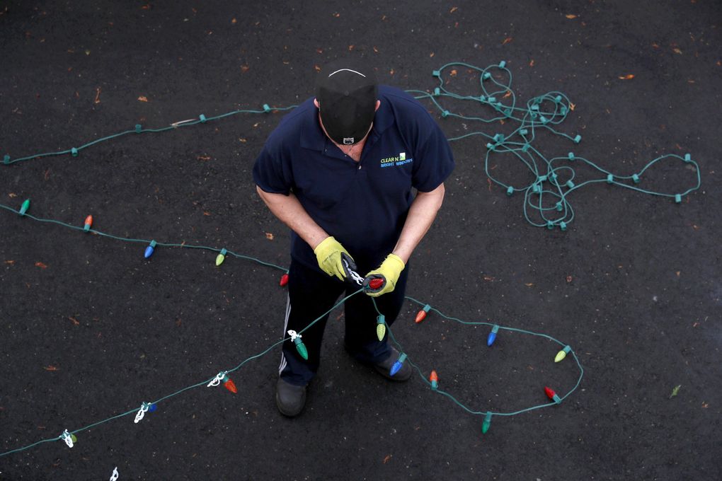 Rob Johnston, owner of Clear N’ Bright Windows, works to install holiday lights in Sultan on Nov. 29, 2018. Clear N’ Bright uses commercial-grade, LED lights without a fuse that can operate for years in a wet climate without needing to be replaced.   (Erika Schultz / The Seattle Times)